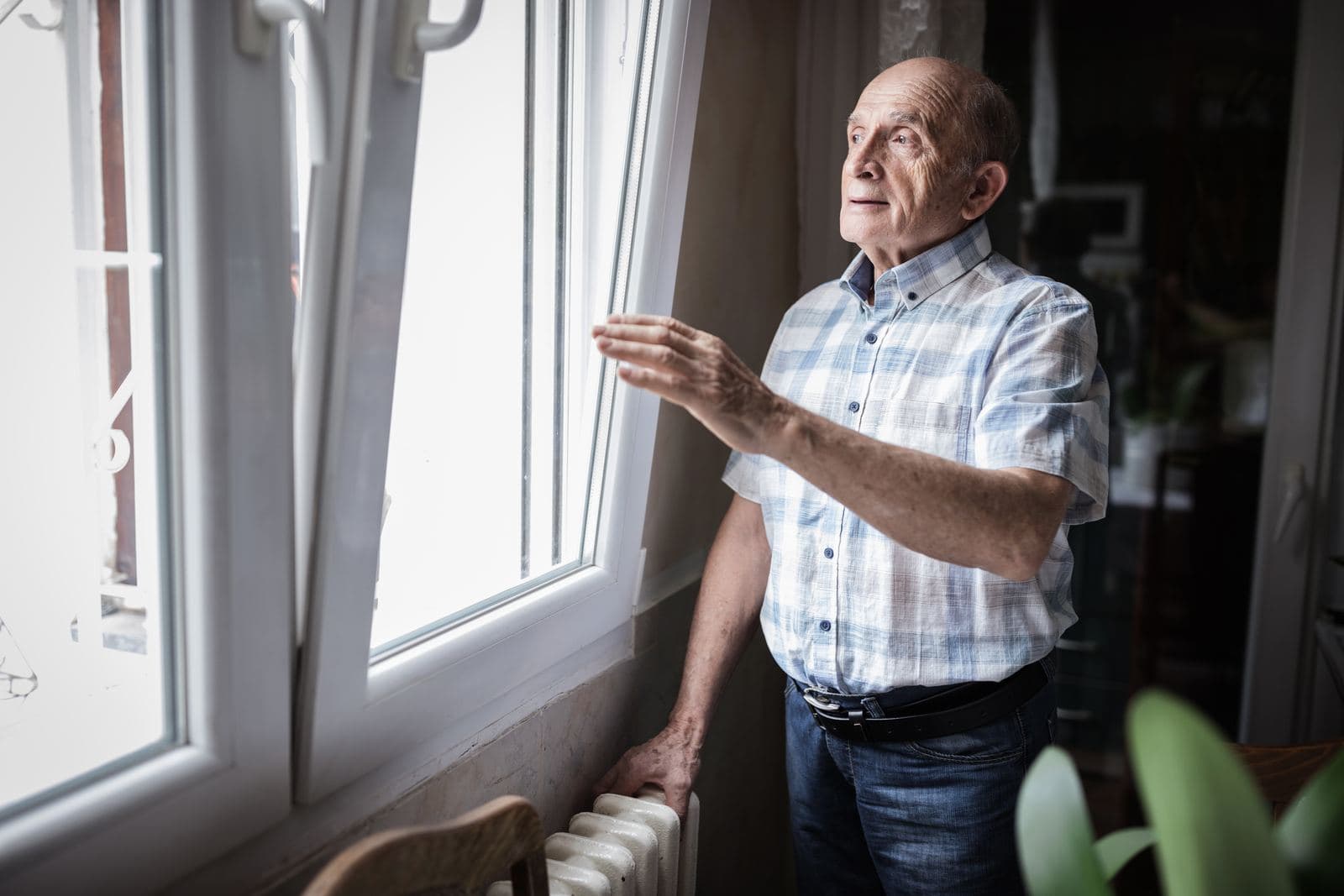 An older man opening a new window above his radiator